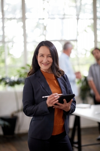 Professional business woman standing, thinking in an open studio - Australian Stock Image