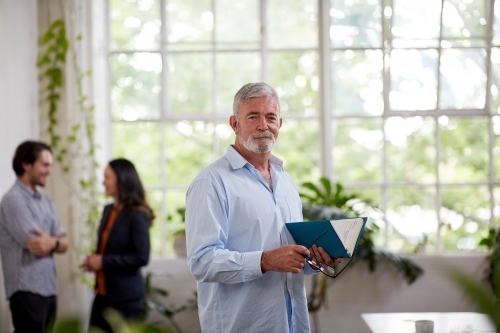 Professional businessman standing in an open studio office - Australian Stock Image