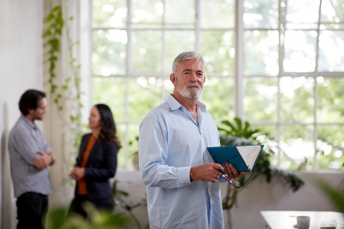 Professional businessman standing in an open studio office - Australian Stock Image
