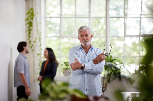 Professional businessman standing, thinking in an open plan office studio - Australian Stock Image