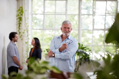 Professional businessman standing, thinking in an open plan office studio - Australian Stock Image