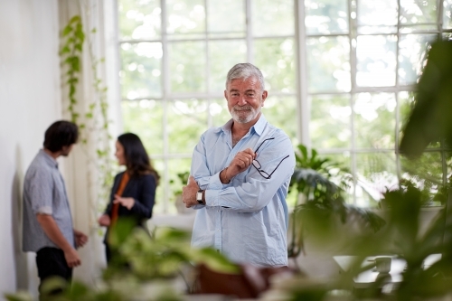 Professional businessman standing, thinking in an open plan office studio - Australian Stock Image