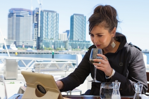 Professional woman working on a tablet over lunch at Docklands in Melbourne - Australian Stock Image