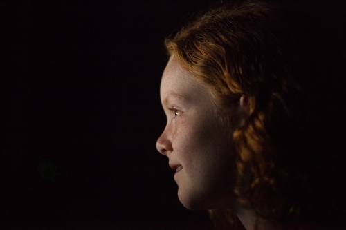 Profile of a young girl in low light - Australian Stock Image