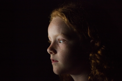 Profile of a young girl in low light - Australian Stock Image