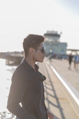 Profile of hispanic male leaning on railing - Australian Stock Image