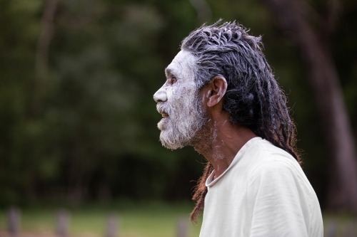 Profile portrait of aboriginal man against a dark bush background