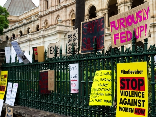 Protest signs on a fence outside a grand old building