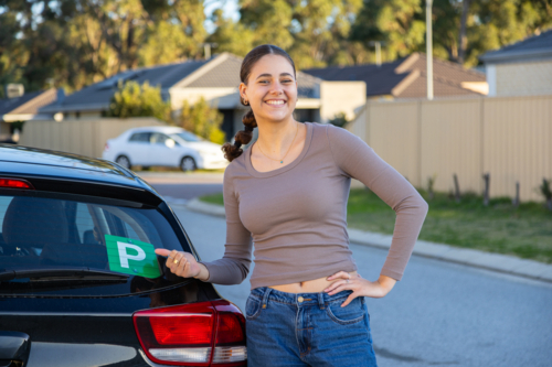 proud teenager indicating green P plate on the back of her car - Australian Stock Image