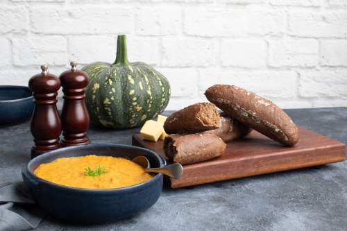 Pumpkin soup scene on dark blue kitchen bench with whole pumpkin - Australian Stock Image