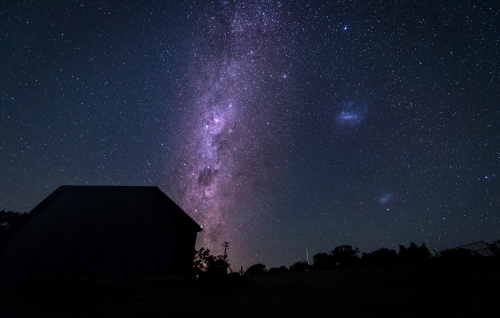 Purple milky way behind silhouetted house