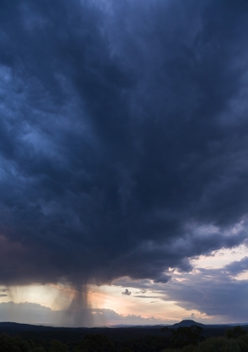 Purple thunderstorm cloud with falling rain and Mount Yengo - Australian Stock Image