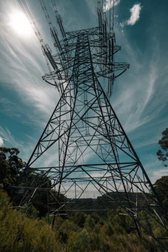 Pylon under vibrant sky in rural greenery, symbolizing modern infrastructure - Australian Stock Image