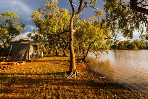 Quiet campsite by an outback lagoon in early morning golden light