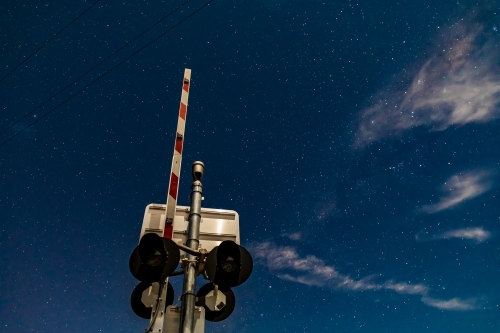 Rail crossing signals and boom barrier against the starry cloudy night sky - Australian Stock Image