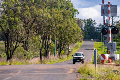 Railway crossing and rail tracks in Queensland countryside during summer - Australian Stock Image