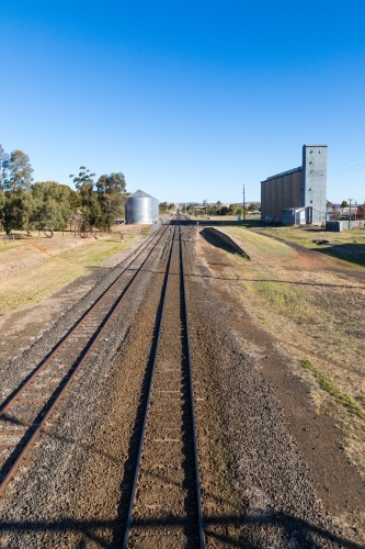 Railway lines leading up to industrial area with rail siding, platform and factory silos - Australian Stock Image