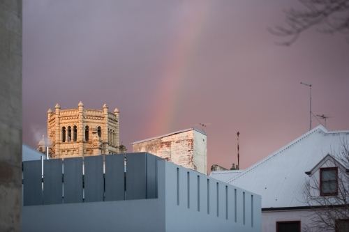 rainbow above buildings in a city - Australian Stock Image