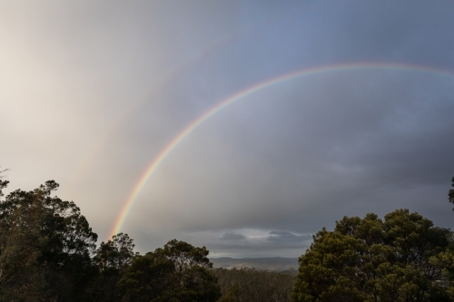 Rainbow above trees and nature scene - Australian Stock Image