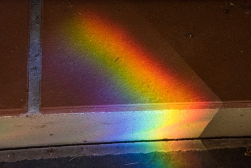 Rainbow coloured light prism shining on tiles - Australian Stock Image