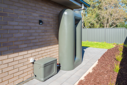Rainwater tank with pump box connected on the backyard of new suburban house in South Australia - Australian Stock Image