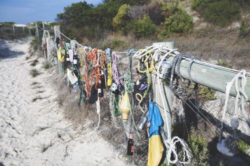 Random fishing and beach gear on fence at the beach - Australian Stock Image