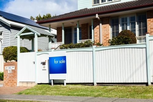 Real estate for sale sign outside white front fence of home in Newcatle - Australian Stock Image