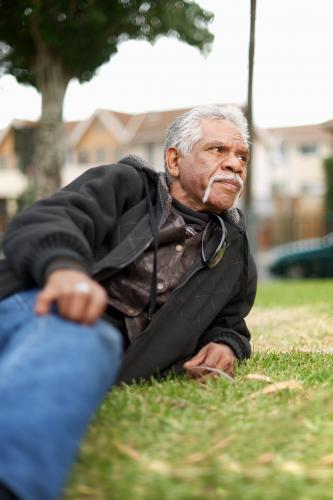 Reclining Aboriginal Man on Grass Outside - Australian Stock Image