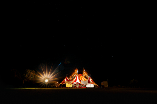 Red and white big top circus tent visiting small town in rural Australia illuminated at night - Australian Stock Image