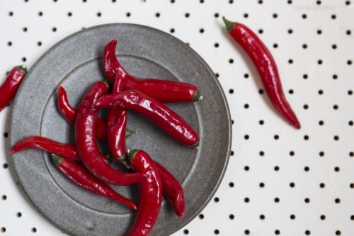 Red Chilli's on grey plate with spotted background - Australian Stock Image
