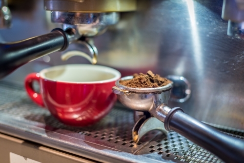 Red coffee cup on coffee machine with ground coffee - Australian Stock Image