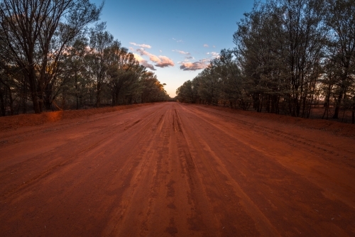 Red dirt road at dusk in Australian outback - Australian Stock Image