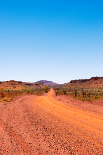 Red dirt road leading to horizon in karijini national park - Australian Stock Image