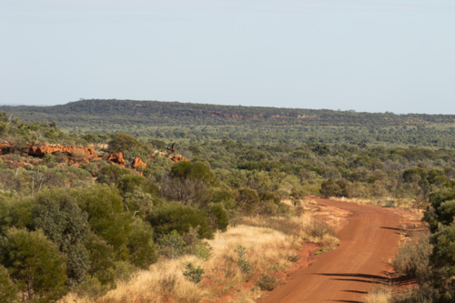 Red dirt road winding around a hill - Australian Stock Image