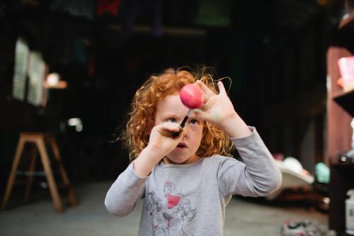 Red haired girl painting an egg - Australian Stock Image