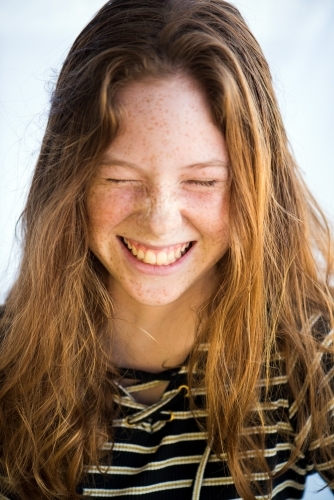 Red haired teenager screwing up face laughing - Australian Stock Image