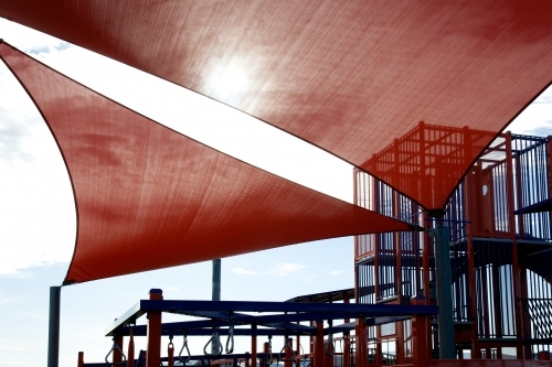Red shade sail above kid's playground - Australian Stock Image