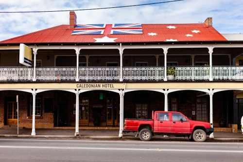 Red ute parked outside of Aussie pub with anti-lockdown australian red ensign flag on roof - Australian Stock Image