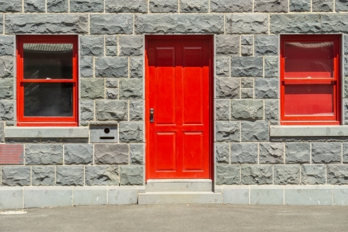 Red windows and doors in the facade of an historic blue stone building - Australian Stock Image