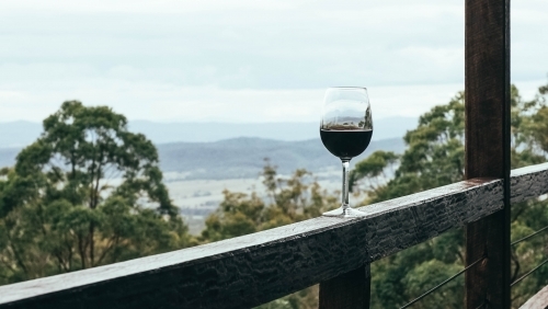 Red wine glass on balcony with a mountain view - Australian Stock Image