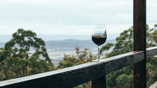 Red wine glass on balcony with a mountain view