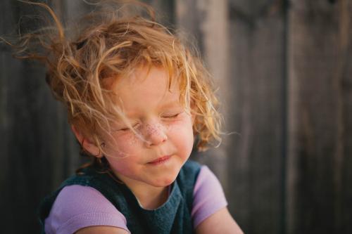 Redhead girl squinting from the wind - Australian Stock Image