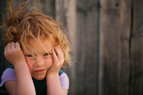Redhead girl squinting from the wind - Australian Stock Image