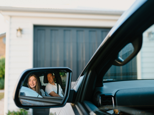 Reflection of a man and young girl inside the car in the rearview mirror. - Australian Stock Image