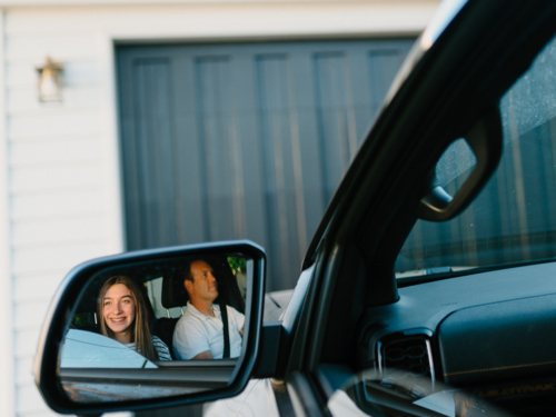 Reflection of a man and young girl inside the car in the rearview mirror. - Australian Stock Image