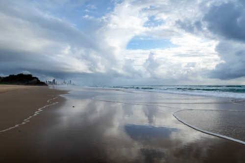 Reflection of sky on beach looking towards city - Australian Stock Image