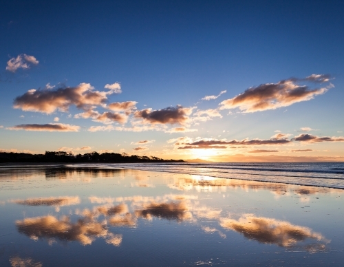 Reflection of sunset sky in wet sand at beach - Australian Stock Image
