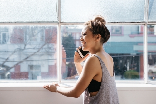 Relaxed girl on the phone in a casual office studio - Australian Stock Image