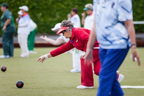 Retired woman delivering  a lawn bowl - Australian Stock Image