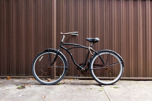 Retro bicycle against brown corrugated iron fence - Australian Stock Image